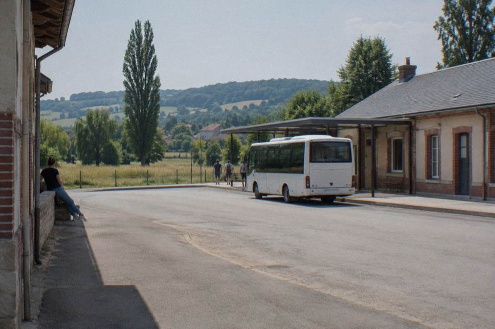A country train platform beside a village station with a green field beyond