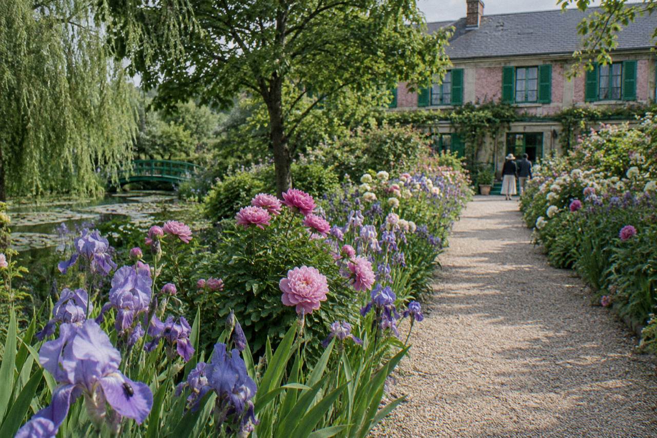 Flower-lined gravel path leading toward the pink facade of Claude Monet's house in Giverny