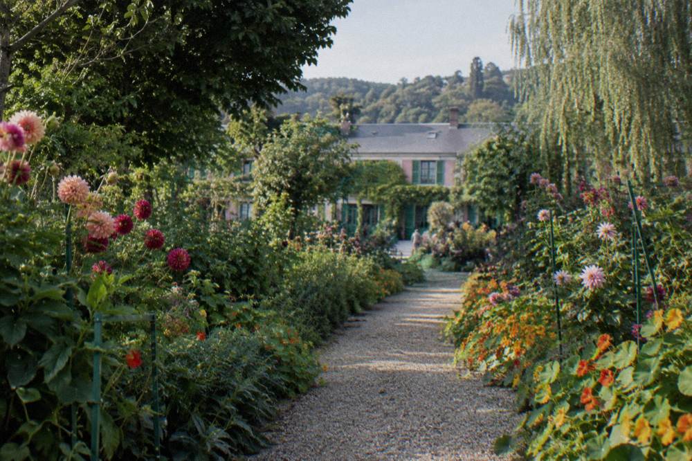 Flower-lined path leading toward the pink facade of Monet's house in Giverny