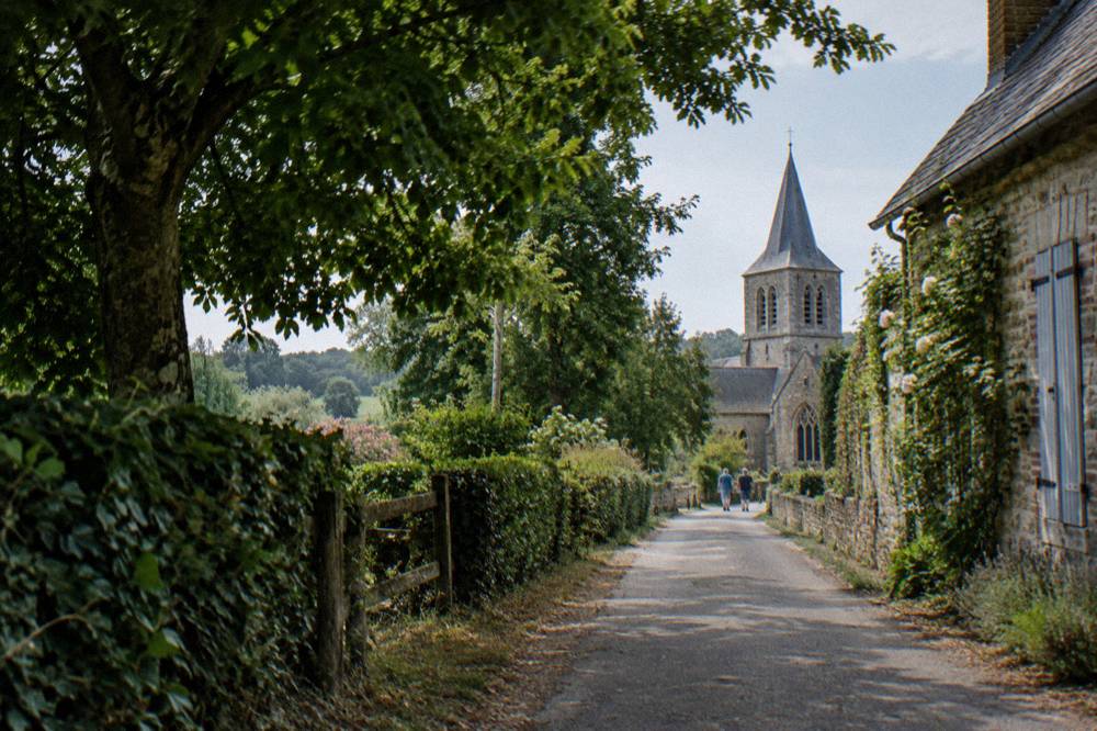 A wooden signpost on a rural lane pointing toward a village church among trees