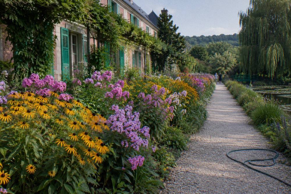 The flower garden in front of Monet's house, with long planted beds and the house facade beyond