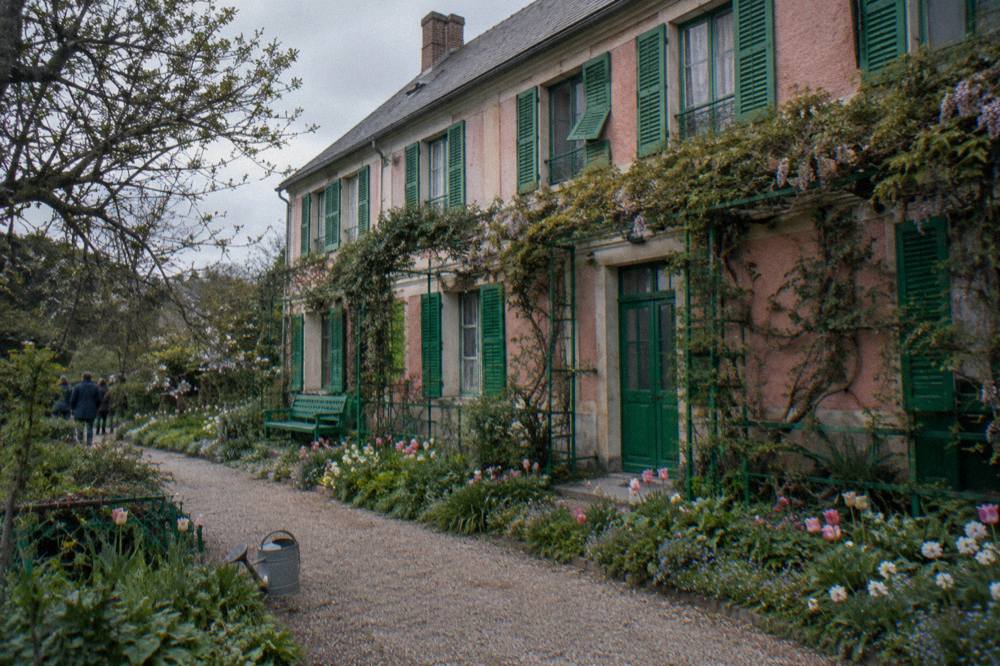 Facade of Monet's pink house seen from the flower garden, with the front door and shuttered windows