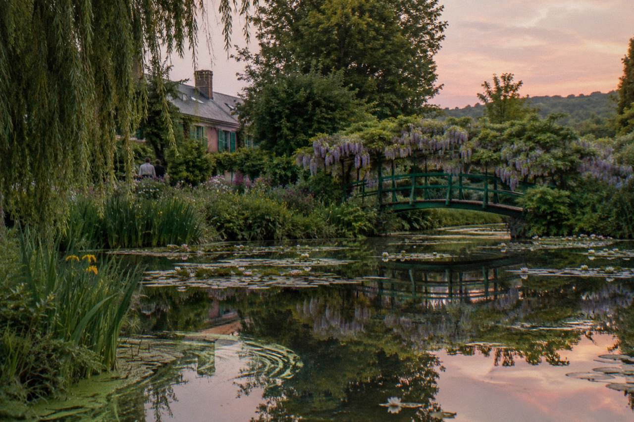 The Japanese bridge over the water lily pond at Monet's garden in Giverny, with greenery reflected in the still water