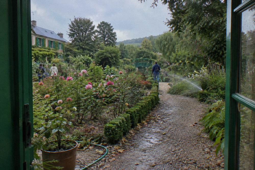 The pink facade of Monet's house seen across the flower beds of the Clos Normand garden