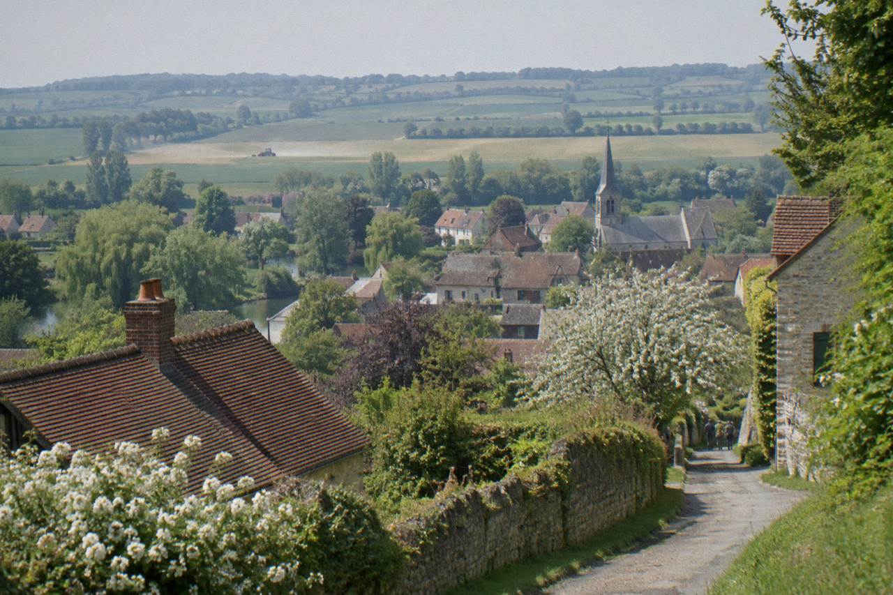 Village houses and a flowering lane in Giverny with rolling Normandy countryside behind