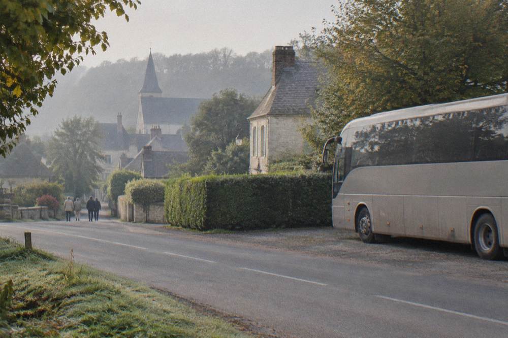 Tour coach parked beside a hedge on the road into Giverny village