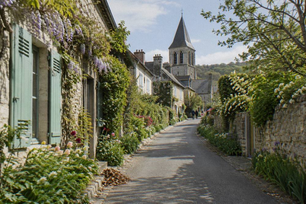 A narrow village street in Giverny with flower gardens beside stone walls