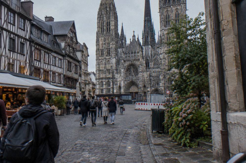 A gothic cathedral facade towering over a half-timbered old town square at dusk
