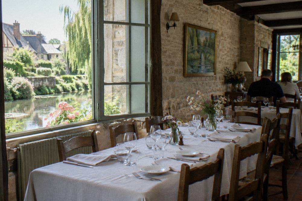 Long table set for lunch inside a bright Normandy restaurant