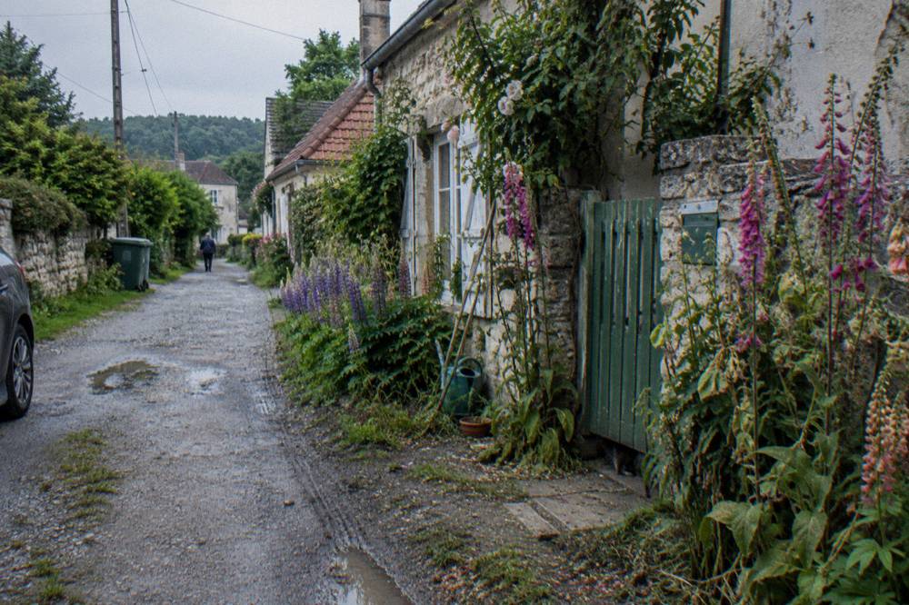 Flower-lined lane in a small Normandy village with stone buildings