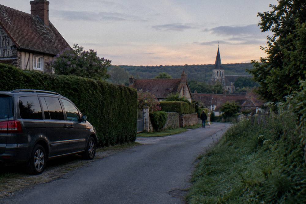 A small minivan parked beside a hedge on a road near Giverny