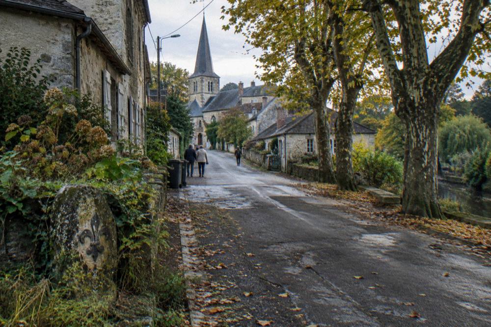 A country road lined with trees leading toward Giverny village