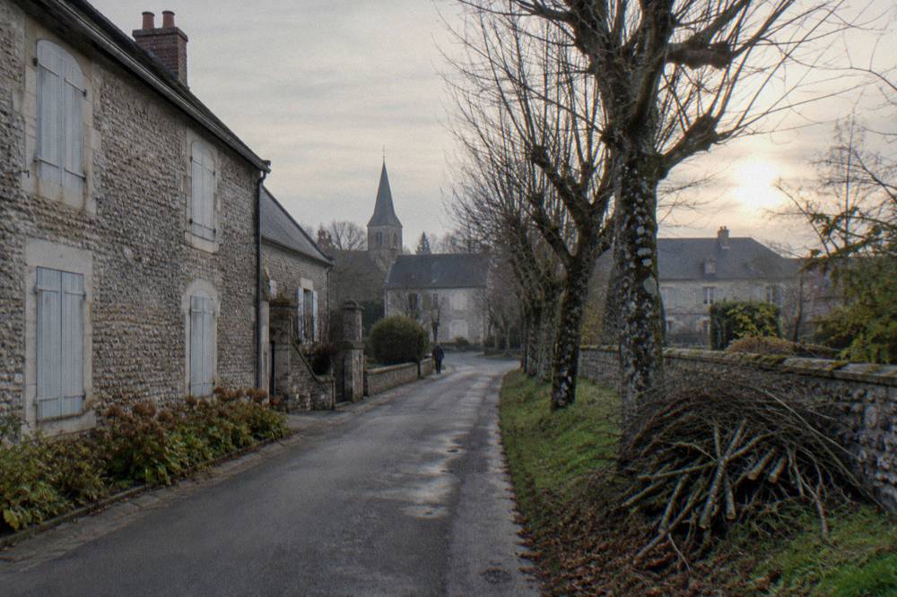 A quiet village street in Giverny with stone houses and bare trees in late autumn