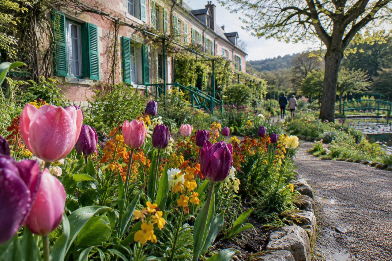 Flower beds and the pink facade of Monet's house in the Giverny garden on a bright morning