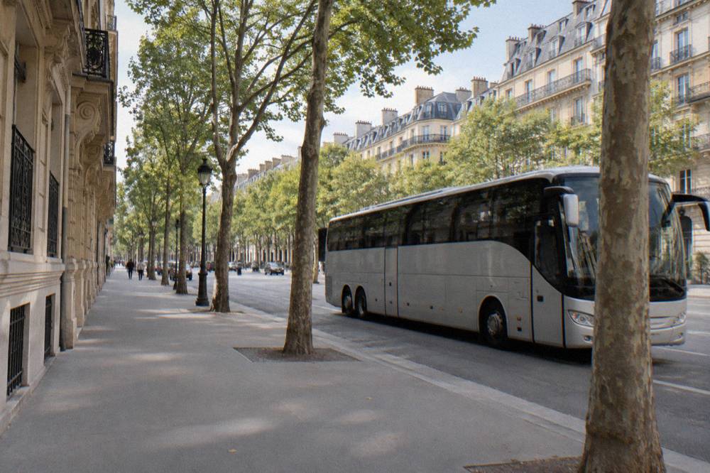 A Paris avenue with a tour coach pulled up beside a wide sidewalk