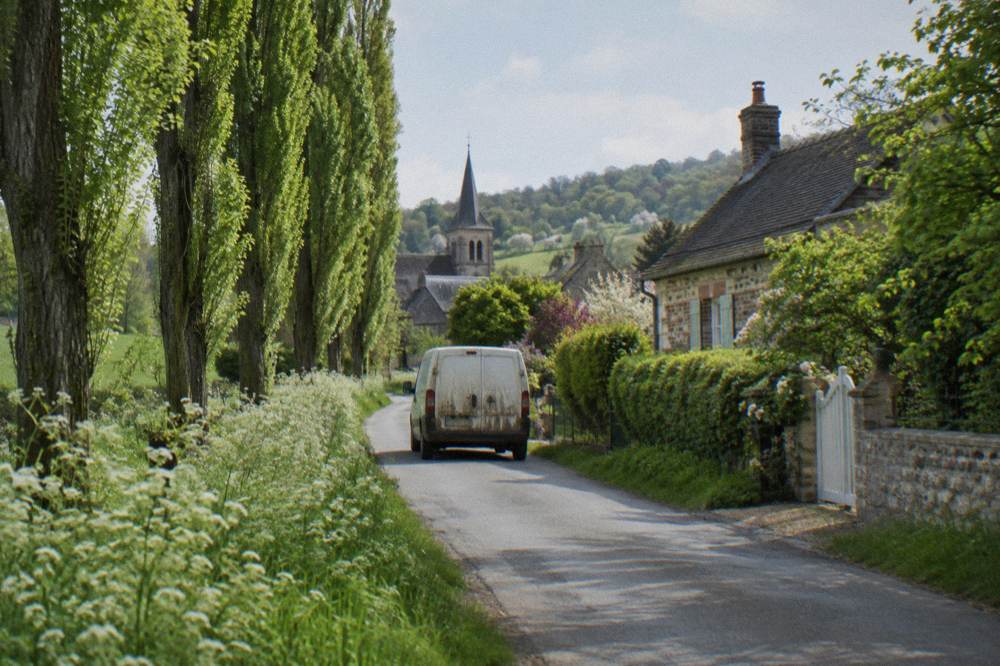 A small van traveling on a country road between Paris and Giverny