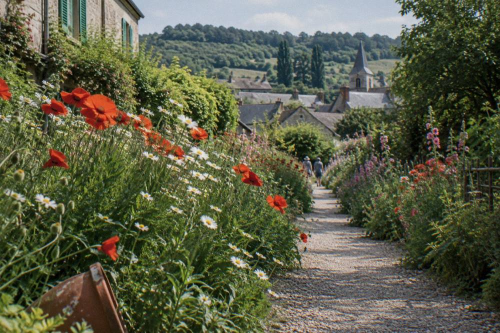 A garden path lined with flowers leading toward the village of Giverny