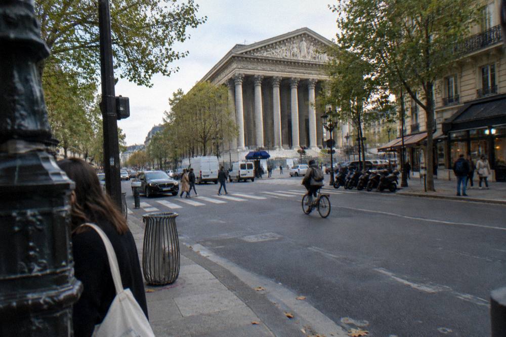 A wide Paris boulevard in early morning with a stone church building at the far side