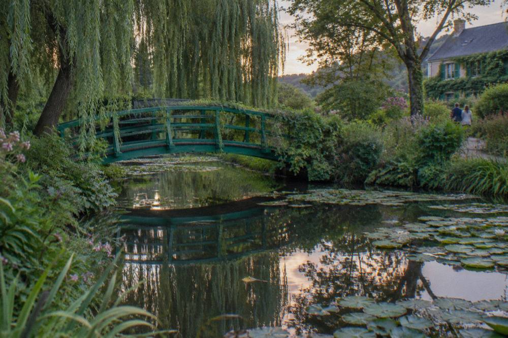 Water lily pond with the green Japanese bridge and willow trees at Monet's garden in Giverny