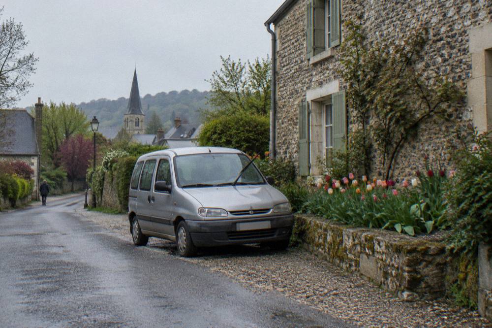 Small passenger minivan parked on a village street beside flower gardens in Giverny