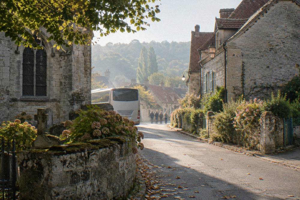 Tour coach parked on a narrow village street lined with stone houses near Monet's garden