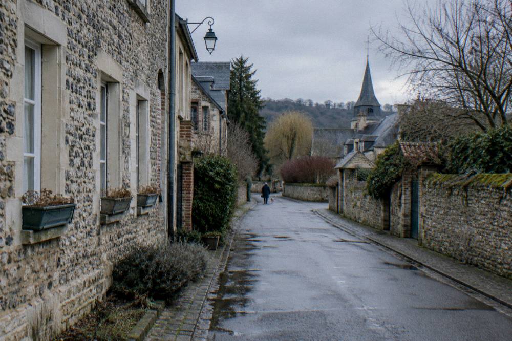 Narrow village street with stone buildings and flowers along the walls