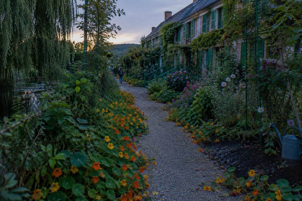 Flower beds in full bloom along the gravel alley of the Clos Normand garden