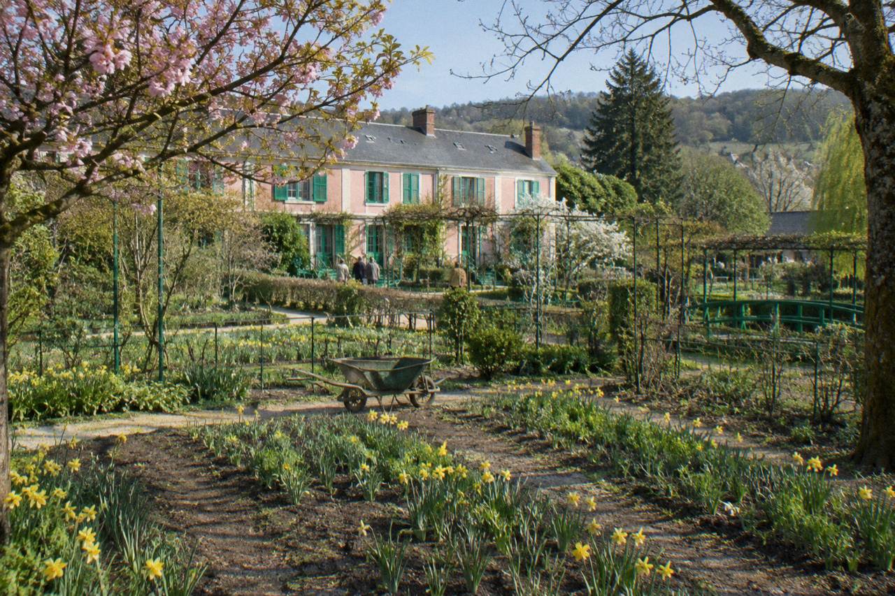 The pink facade of Monet's house seen across the flower beds of the Clos Normand garden