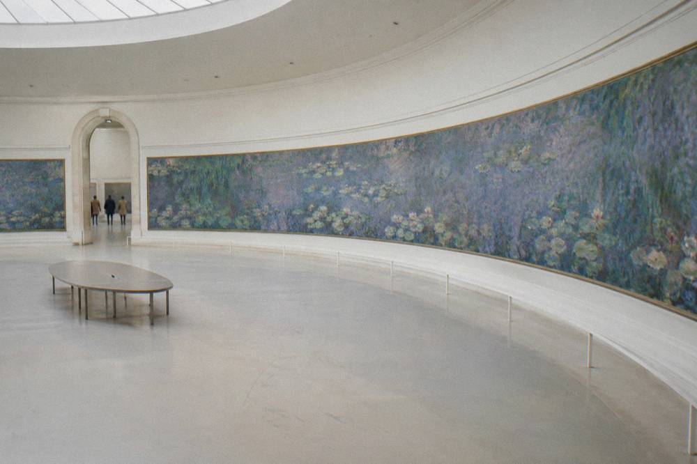 Oval gallery wall with curved panorama paintings in diffused light