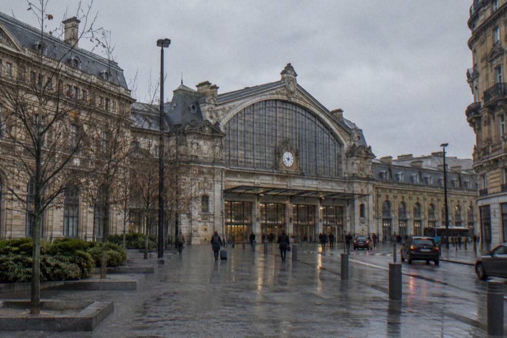 The facade of a Paris railway terminus with travelers heading to the platforms