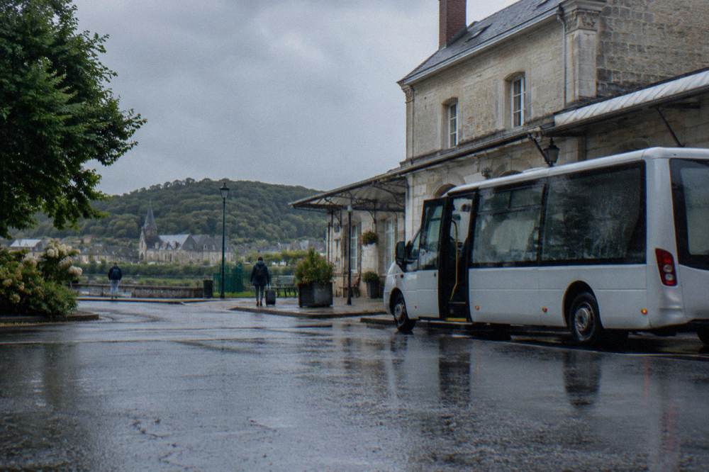 A shuttle bus parked at a small town station waiting for arriving passengers
