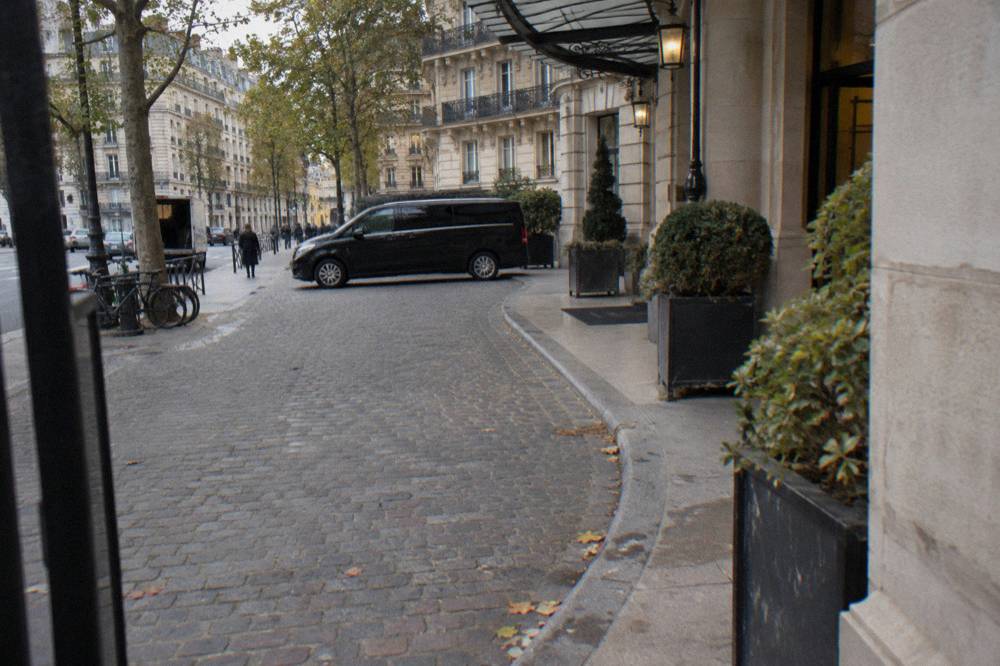 A hotel driveway in central Paris with a waiting Mercedes minivan at morning departure time