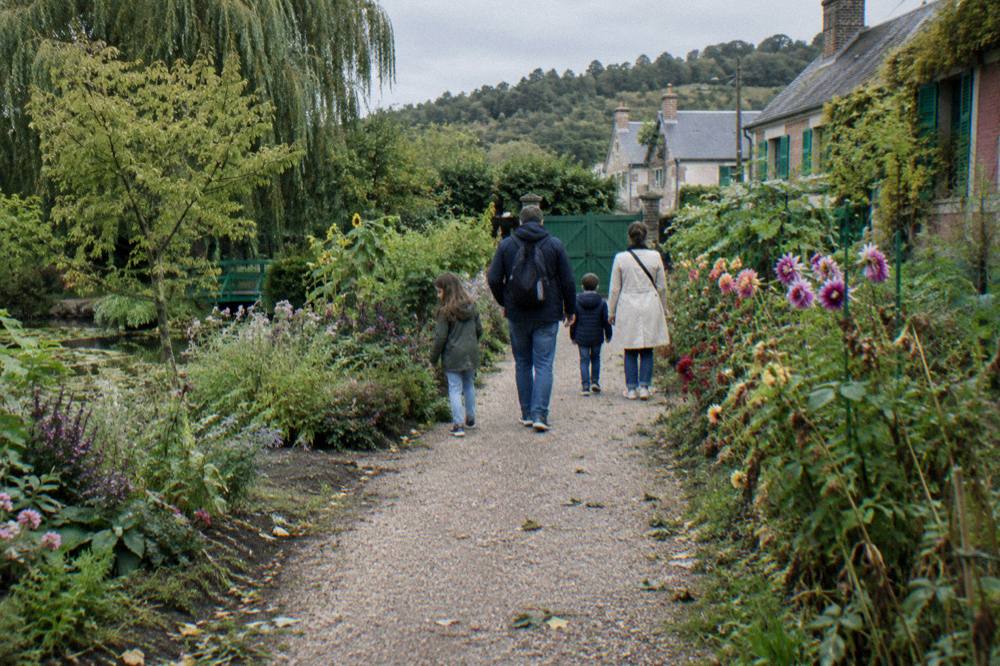 A family walking back down the Grande Allée toward the garden gate in the late afternoon