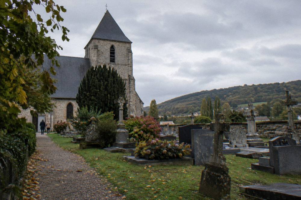 An old stone church tower above gravestones in a small churchyard