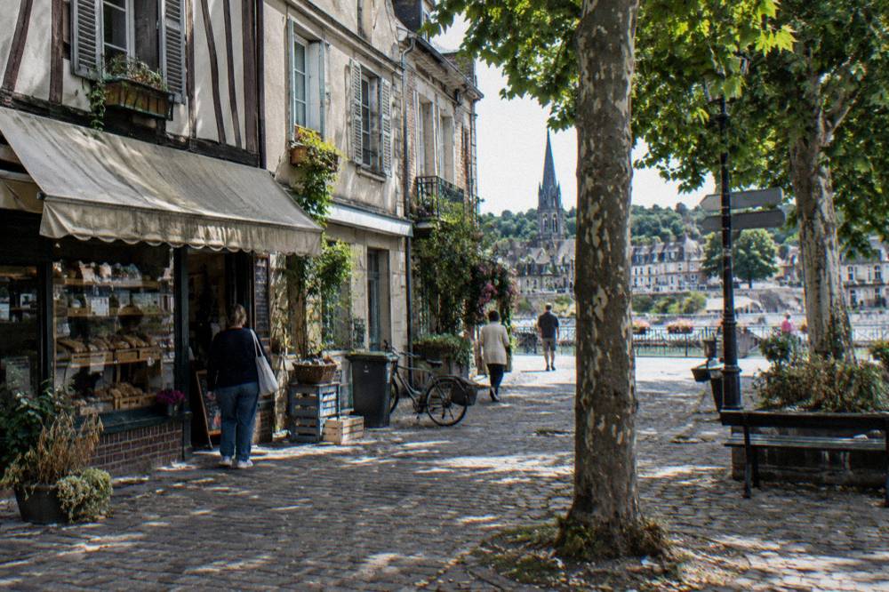 Small town square with bakery storefront and parked bicycles under trees