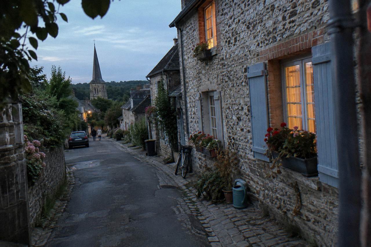 Stone houses and flower boxes along a quiet village street in Giverny at dusk
